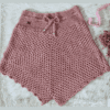 Handmade crochet shorts named 'Chantalle Cover Up Shorts' by Arty-Crafty by Vanessa, crafted from a mix of cotton and acrylic yarn in a delicate pink hue, featuring an adjustable waist tie