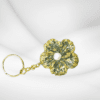 Handmade flower keychain with green and gold accents, featuring a pearl center, created by Maryam.