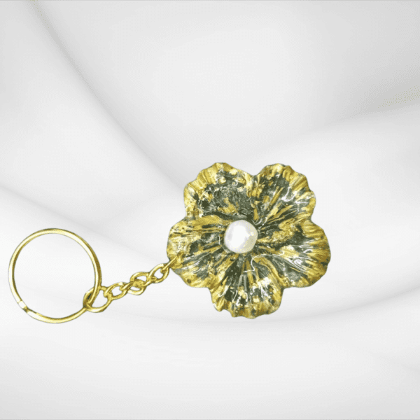 Handmade flower keychain with green and gold accents, featuring a pearl center, created by Maryam.