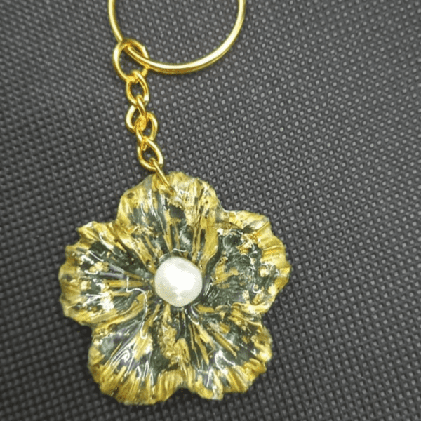 Handmade flower keychain with green and gold accents, featuring a pearl center, created by Maryam.