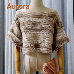 Handmade beige-colored crochet top named 'Aurora Top' by Arty-Crafty by Vanessa, featuring a lightweight, free-size design made from cotton and acrylic yarn, displayed on a mannequin with a matching crochet clutch.