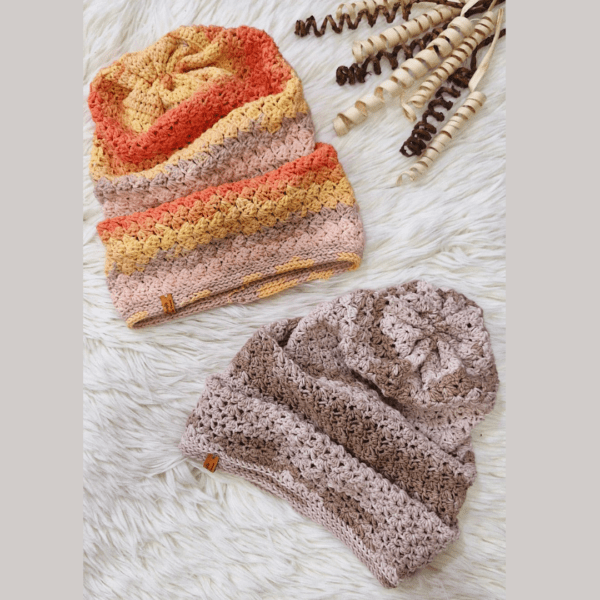 Handmade crochet beanies named 'CHELLY BEANIE HAT' by Arty-Crafty by Vanessa, featuring warm, multicolored designs made from a blend of cotton and acrylic yarn, displayed on a soft white surface with natural decorative elements.