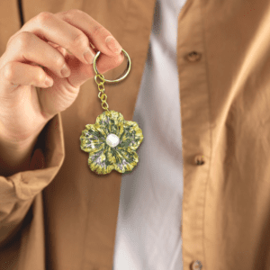 Handmade flower keychain with green and gold accents, featuring a pearl center, created by Maryam.