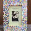 Colorful Rainbow Mosaic Frame displayed on a wooden table, featuring vibrant square tiles in various colors surrounding a 4x6 inch photo. The frame adds a lively and artistic touch to the decor.