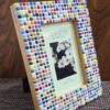 Colorful Rainbow Mosaic Frame displayed on a wooden table, featuring vibrant square tiles in various colors surrounding a 4x6 inch photo. The frame adds a lively and artistic touch to the decor.