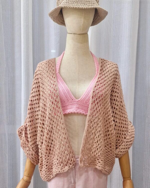 Handmade rose-colored cotton kimono top named 'Suzy - Kimono Top' by Arty-Crafty by Vanessa, featuring a loose, free-size design with wide sleeves, displayed on a hanger against a colorful background.