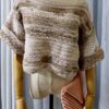 Handmade beige-colored crochet top named 'Aurora Top' by Arty-Crafty by Vanessa, featuring a lightweight, free-size design made from cotton and acrylic yarn, displayed on a mannequin with a matching crochet clutch.