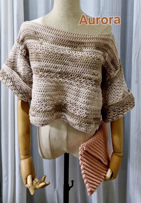 Handmade beige-colored crochet top named 'Aurora Top' by Arty-Crafty by Vanessa, featuring a lightweight, free-size design made from cotton and acrylic yarn, displayed on a mannequin with a matching crochet clutch.