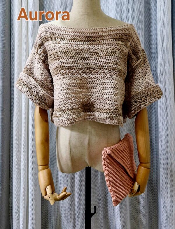 Handmade beige-colored crochet top named 'Aurora Top' by Arty-Crafty by Vanessa, featuring a lightweight, free-size design made from cotton and acrylic yarn, displayed on a mannequin with a matching crochet clutch.