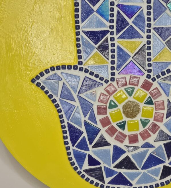 Handcrafted Evil Eye Hamsa Hand Mosaic, featuring a vibrant yellow background and intricate blue and multicolored mosaic tiles forming the protective Hamsa symbol