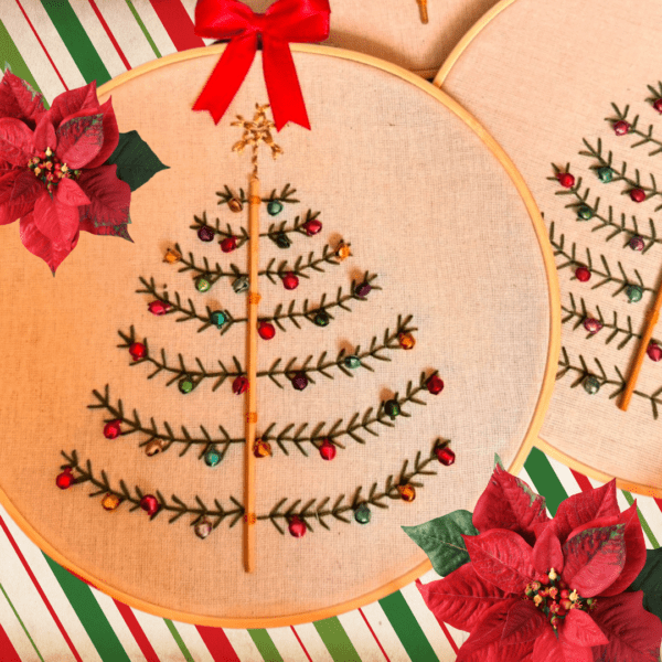 Hand-embroidered Christmas tree wall art with colorful ornaments, framed in a 5-inch wooden hoop with a red bow, created by Anu Paulson.