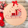 Hand-embroidered wall art featuring a Christmas sleigh filled with gifts, framed in an 8-inch wooden hoop with a festive red bow, created by Anu Paulson.