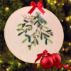 Hand-embroidered Christmas mistletoe wall art featuring green mistletoe leaves, red berries, and silver bells, framed in an 8-inch wooden hoop with a red ribbon, created by Anu Paulson.