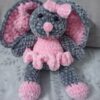 Handmade bunny plushie made with soft gray and pink velvet yarn, featuring floppy ears, a pink bow, and an adorable outfit. Perfect for babies and toddlers as a soft toy or baby shower gift.