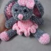 Handmade bunny plushie made with soft gray and pink velvet yarn, featuring floppy ears, a pink bow, and an adorable outfit. Perfect for babies and toddlers as a soft toy or baby shower gift.