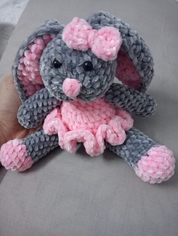 Handmade bunny plushie made with soft gray and pink velvet yarn, featuring floppy ears, a pink bow, and an adorable outfit. Perfect for babies and toddlers as a soft toy or baby shower gift.