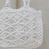 Handcrafted pure white macrame bag with intricate knotting, compact size, 19 cm wide, 16 cm high, and 5 cm deep.