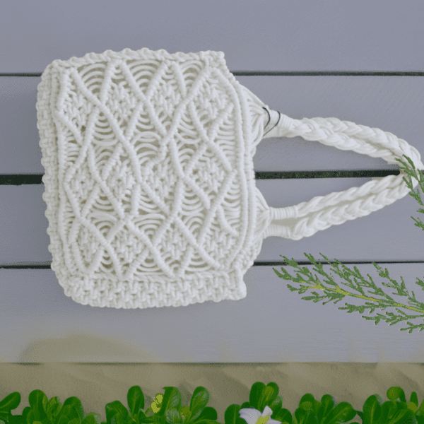 Handcrafted pure white macrame bag with intricate knotting, compact size, 19 cm wide, 16 cm high, and 5 cm deep.