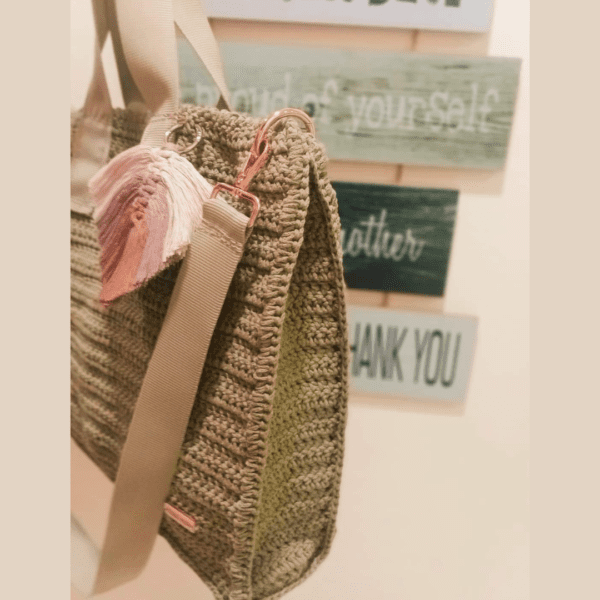 Handmade crochet Vhalerie Bag in black, featuring a detachable and adjustable strap, metallic snap button fastener, and decorative macramé leaf charm. The bag measures 14 inches in height, 16 inches in length, and 3 inches in width.