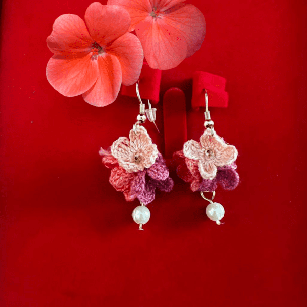 Handmade pink crochet flower earrings with pearl accent, delicate floral design.