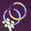 Handmade macrame earrings in pastel unicorn colors (pink, purple, blue, yellow), circular hoop design by Rita Lewis.