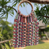 Multicolor handwoven macrame bag with wooden handle, zipper closure, and cotton lining, 12 inches wide and 18 inches long.