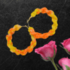 Handmade twisted macrame earrings in marigold shades of yellow and orange, circular hoop design by Rita Lewis.