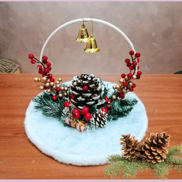 Festive pine cone decoration with berries, bells, and greenery on a wooden base.