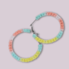 Handmade Lutino macrame earrings featuring pastel colors in a circular hoop design by Rita Lewis.