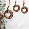 Handmade red and green macrame Christmas ornament with a 2.25-inch diameter, featuring classic holiday colors.