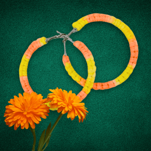 Handmade macrame earrings in bright yellow and orange, circular hoop design by Rita Lewis.