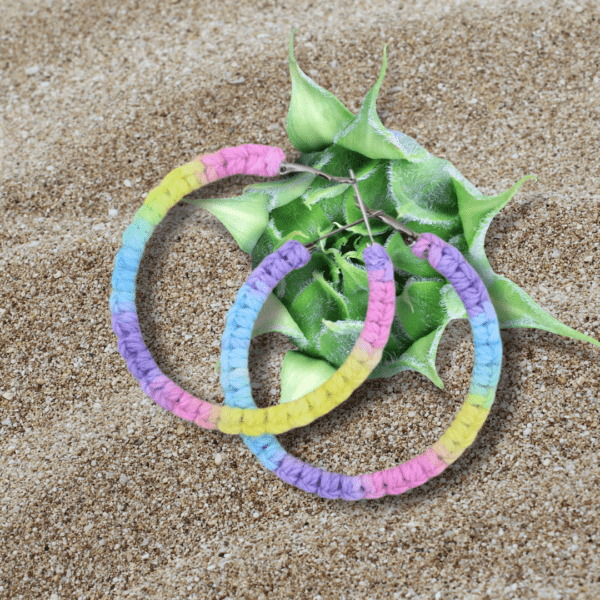 Handmade macrame earrings in pastel unicorn colors (pink, purple, blue, yellow), circular hoop design by Rita Lewis.