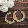 Handmade twisted macrame earrings in pastel Lutino colors (yellow, peach, blue), circular hoop design by Rita Lewis.