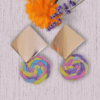 Handmade earrings with square metal stud and round macrame dangle in pastel unicorn colors (pink, blue, yellow, purple), designed by Rita Lewis.