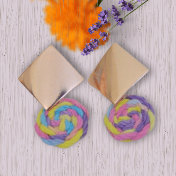 Handmade earrings with square metal stud and round macrame dangle in pastel unicorn colors (pink, blue, yellow, purple), designed by Rita Lewis.