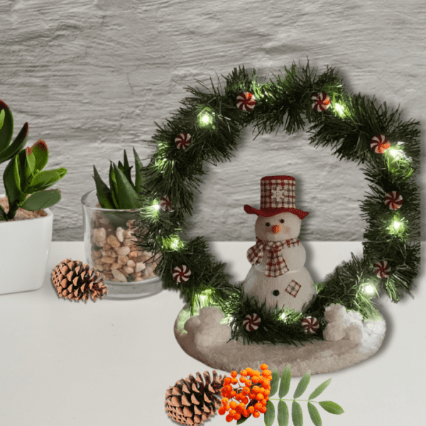 Snowman holiday decoration with LED lights and peppermint accents on a wooden base.