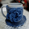 Handmade Blissful Brew Set featuring a crochet mug cover and matching coaster. Customizable colors include blue, red, green, and festive patterns. A perfect gift for tea and coffee lovers.