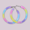 Handmade macrame earrings in pastel unicorn colors (pink, purple, blue, yellow), circular hoop design by Rita Lewis.