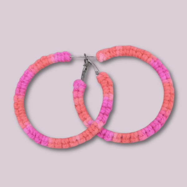 Handmade macrame earrings in vibrant pink and coral hues, circular hoop design by Rita Lewis