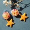 Handcrafted yellow star clip-on earrings with floral resin studs, lightweight at 2g, 3.5 cm long, with gold-plated stainless steel backs