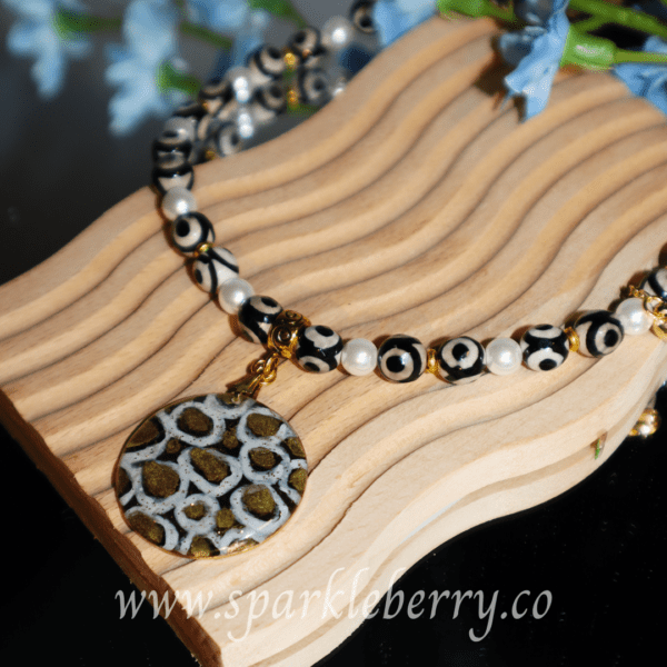 Adjustable necklace with Dzi Agate and shell beads, featuring a hand-painted resin pendant. Can be worn as a choker or long necklace. Brings style and positive energy