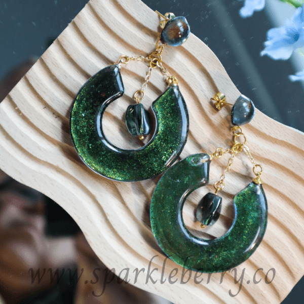 Handcrafted emerald green drop earrings with crescent design, gold-plated chains, lightweight at 9g, and 7 cm long