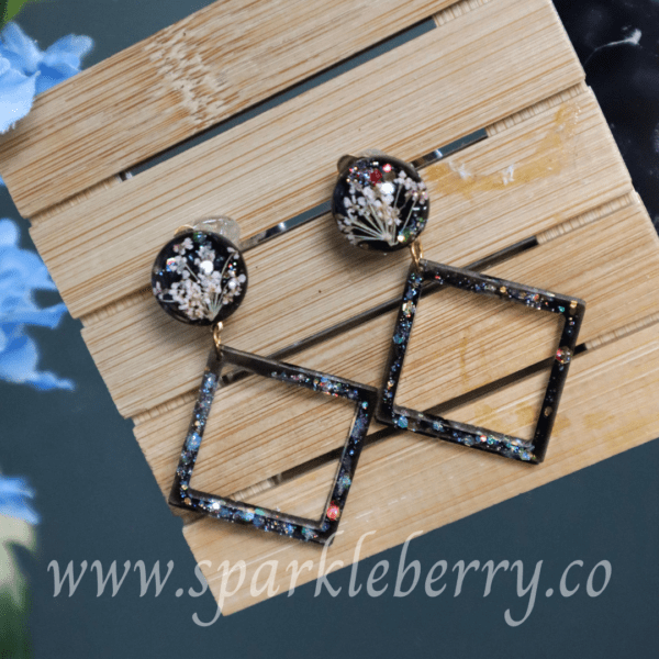 Handcrafted clip-on earrings with dried flowers, resin, geometric glitter frame, and hypoallergenic stainless steel backs, lightweight at 3g, and 6 cm long