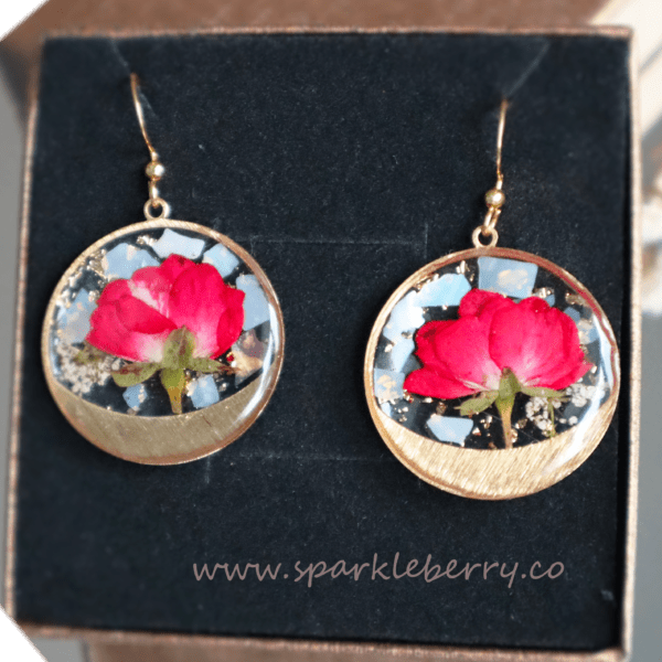 Romantic rose gold earrings featuring real red roses and gold foil accents encased in resin, with hypoallergenic gold-plated hooks.