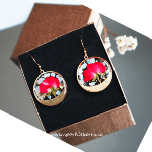 Romantic rose gold earrings featuring real red roses and gold foil accents encased in resin, with hypoallergenic gold-plated hooks.