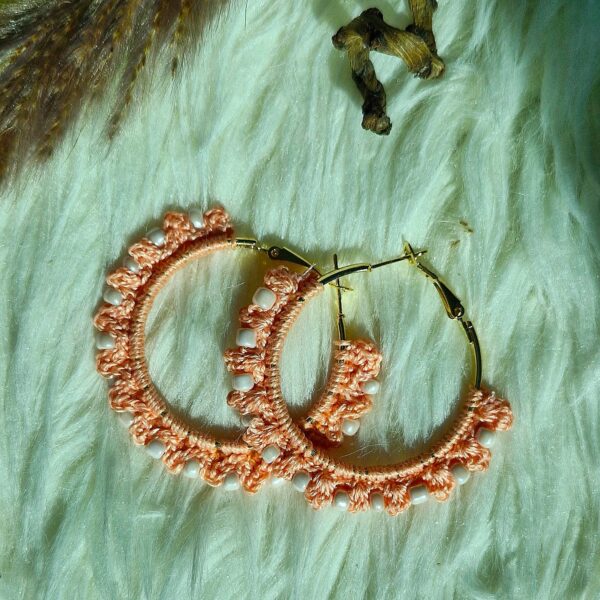 Close-up of handcrafted crochet hoop earrings with beads, available in multiple colors including peach, cream, black, and green.