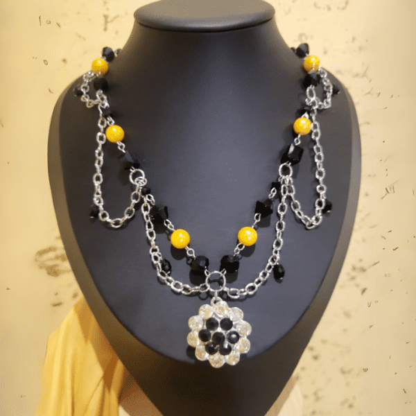 Handmade layered necklace by Nel’s Jewels with black and yellow glass beads. Features silver chains and a floral beaded pendant. Perfect for any occasion!