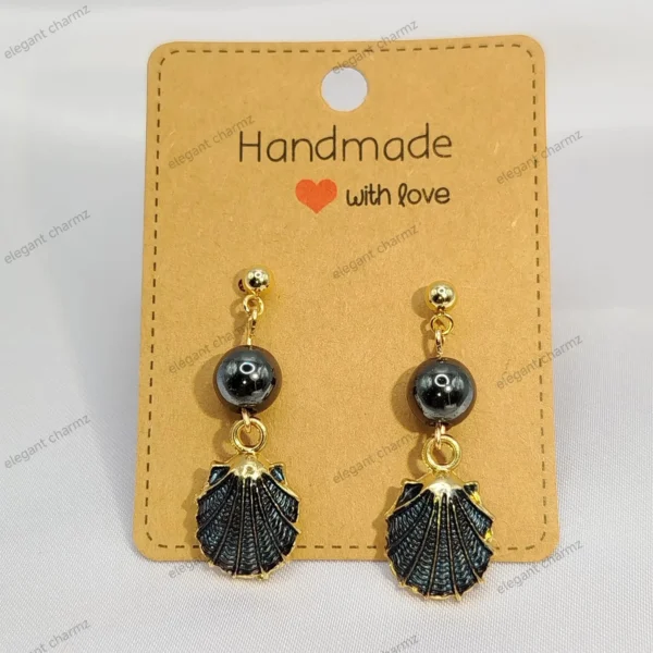 A pair of elegant dark blue bead dangle earrings with gold-plated shell charms and stainless steel ear studs, displayed on a handmade jewelry card.