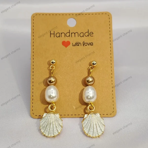 A pair of elegant pearl bead dangle earrings with gold-plated shell charms and stainless steel ear studs, displayed on a handmade jewelry card.