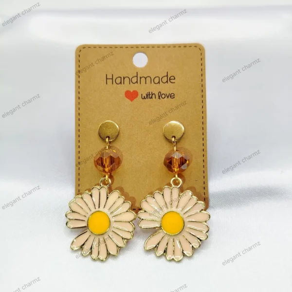 Handmade daisy flower earrings with gold-tone accents and amber crystal beads, displayed on a craft paper card